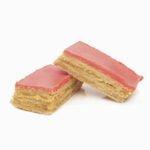 Milhojas Rosas Láminas de hojaldre unidas una encima de otra por crema pastelera. La lámina superior tiene una capa de cobertura rosas